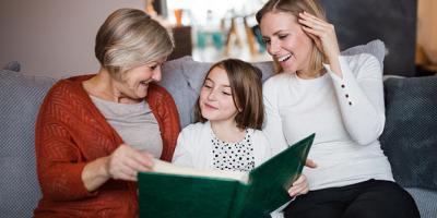 A young girl with mother and grandmother looking through a photo album.