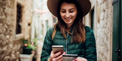 Woman using credit card and mobile phone while traveling