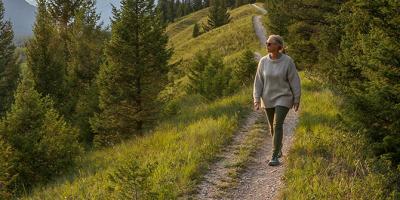 Older woman walking and looking out to mountain ranges in distance