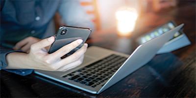 Hands holding smart phone and laptop at the same time