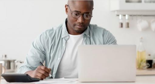 man using laptop computer, sitting in kitchen