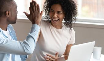 Couple sit near computer high-fiving