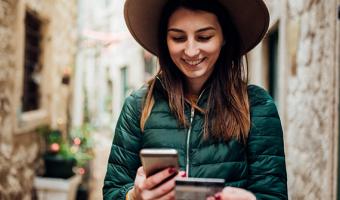 Woman using credit card and mobile phone while traveling