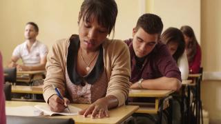 Students in class taking notes. Saving for College video.