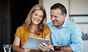 Couple reviewing paperwork on a digital tablet from home.