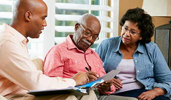 Financial Advisor Talking To Senior Couple At Home.