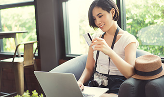 Young woman traveler holding a credit card while she's on laptop.