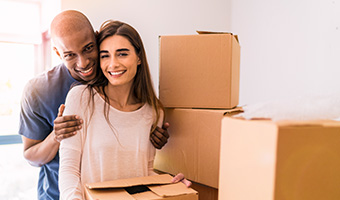 Portrait of couple with boxes in new house.